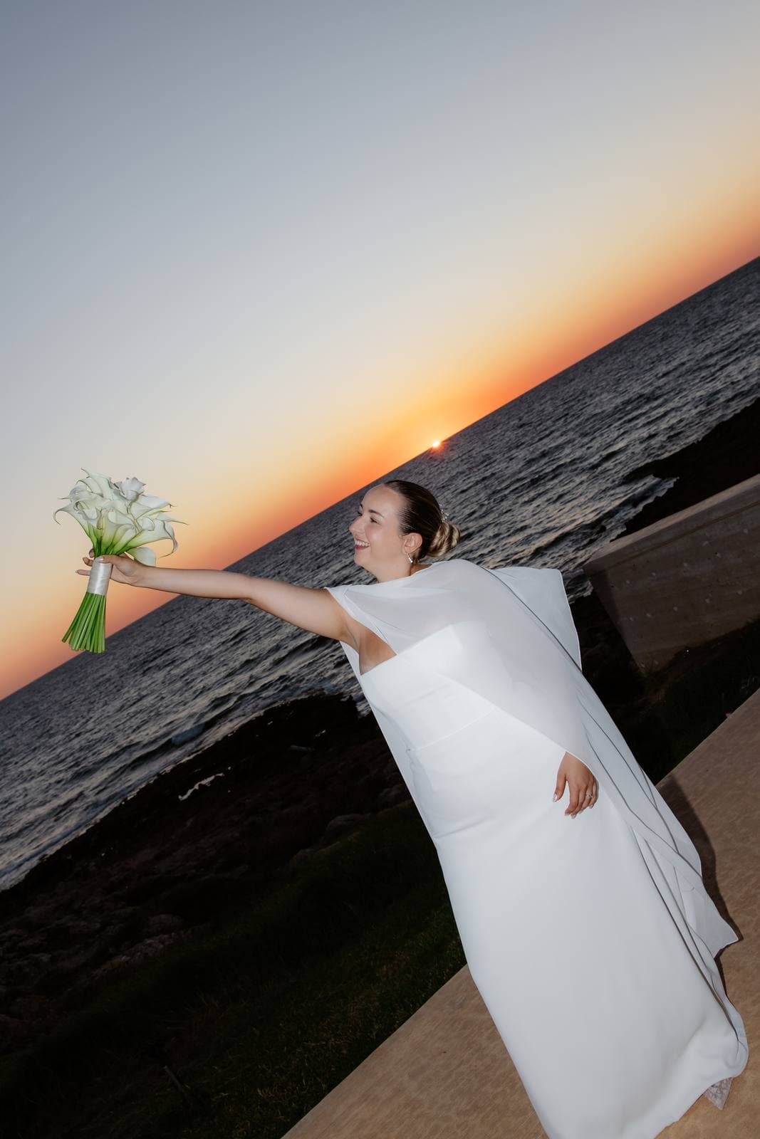 Christos & Eleni, the bride holding up her bouquet at sunset