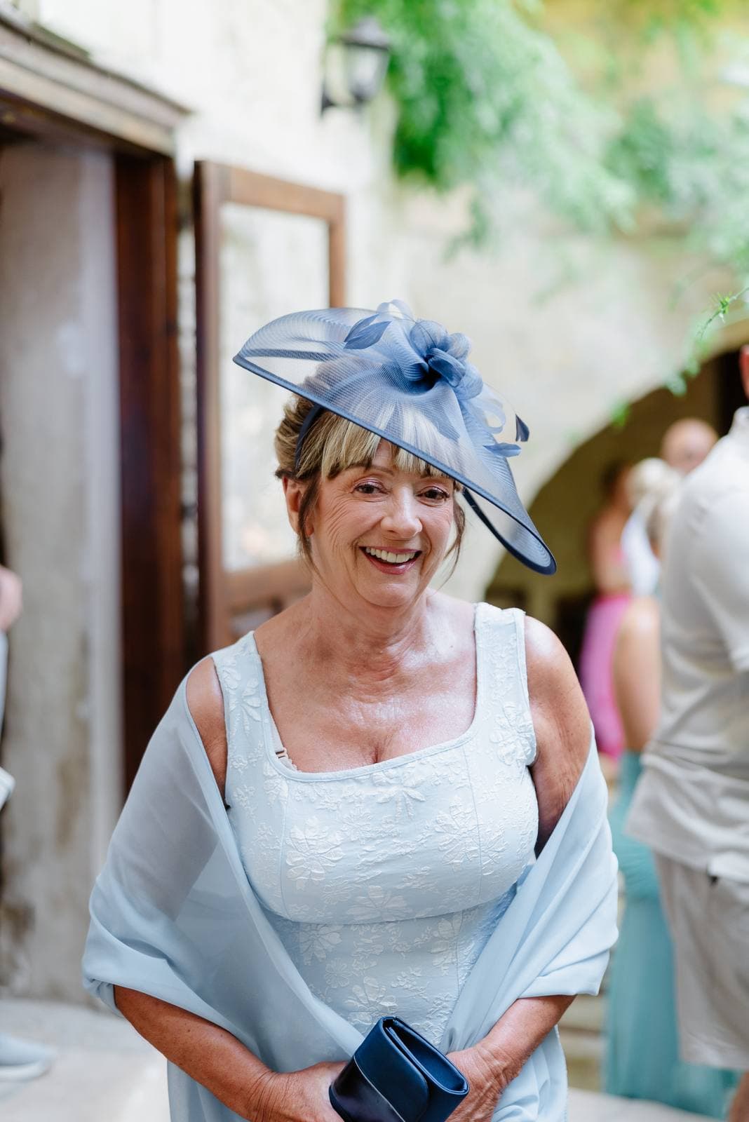 Hannah & Danial, a guest in a blue fascinator in the courtyard