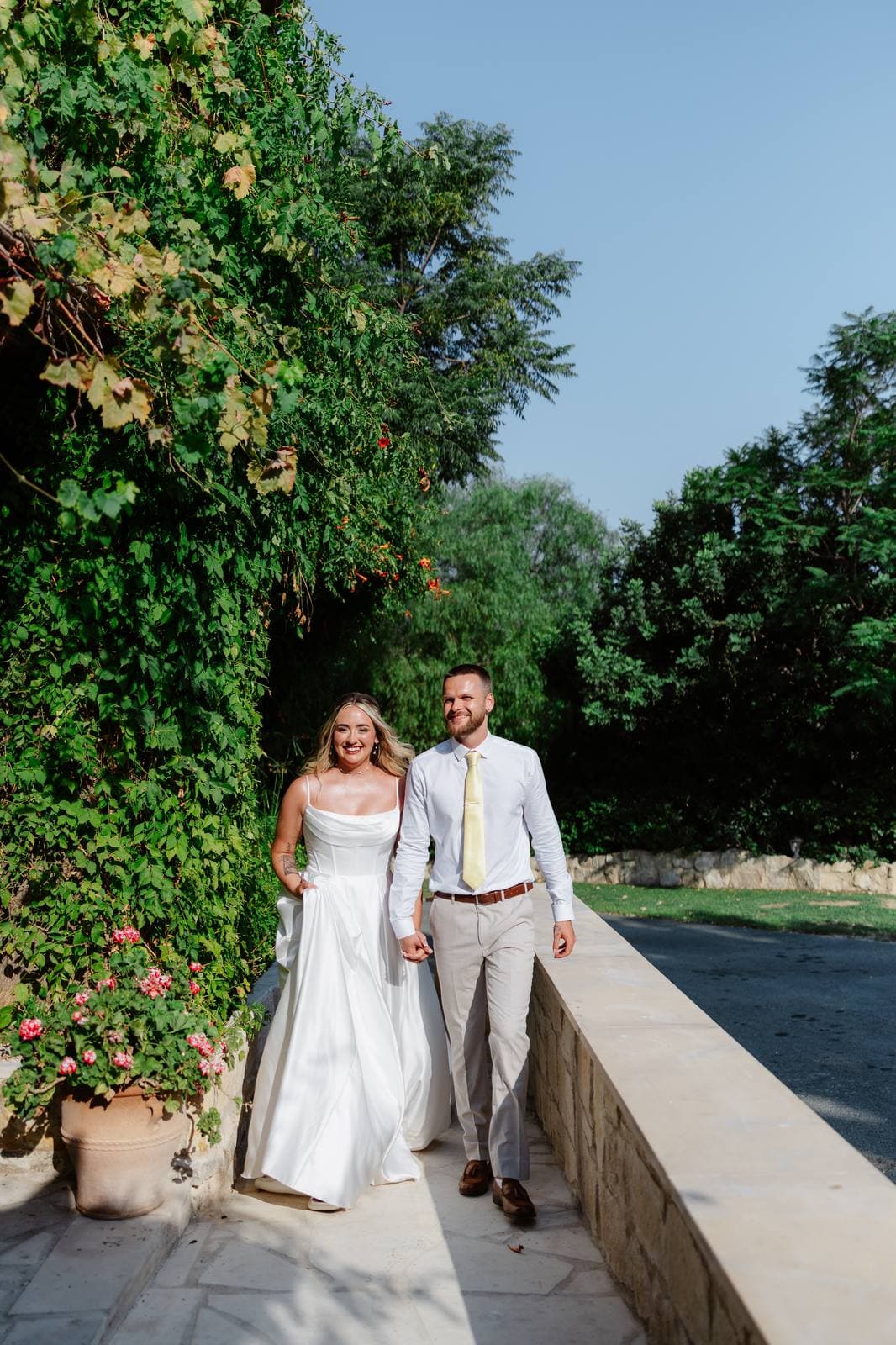 Hannah & Danial, bride and groom walking by the stone wall