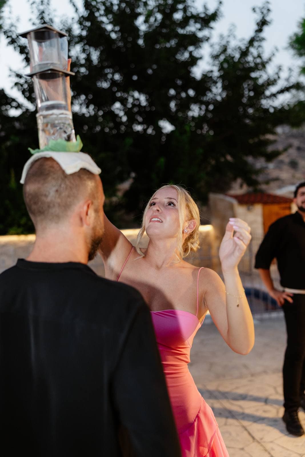 Hannah & Danial, greek dancers balancing glasses with a guest