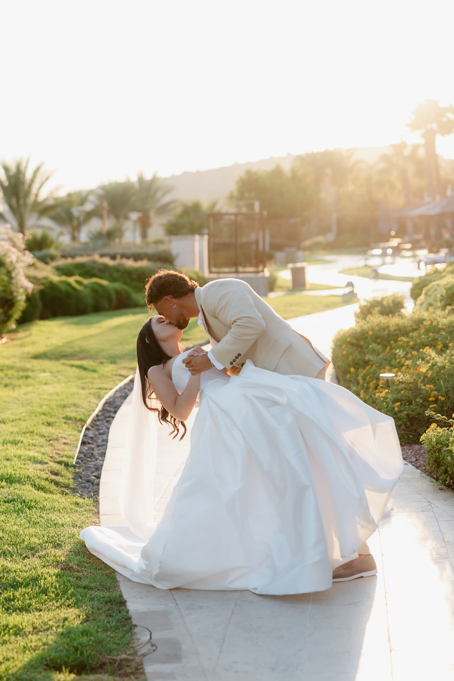 The groom dips his bride for a kiss in the gardens at Amara, Limassol