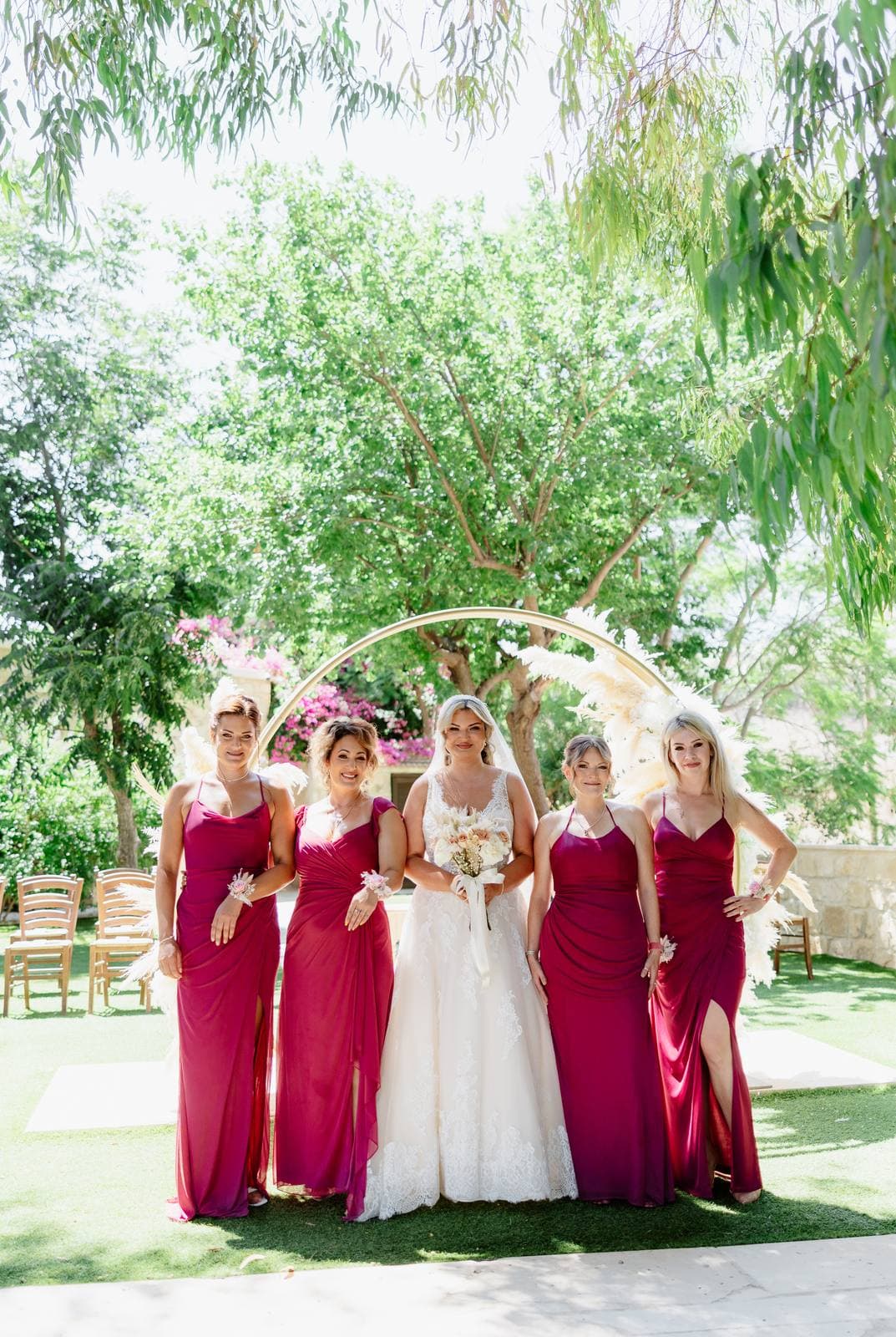 Rita & Andrej, the bride and bridesmaids in berry dresses by the arch