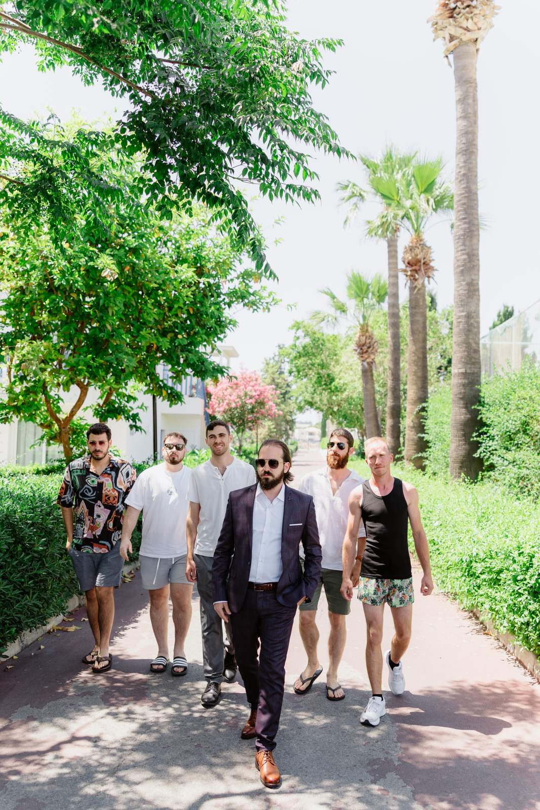 Sivan & Elon, the groomsmen walking under the palms